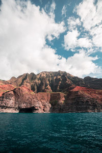 Scenic view of rock mountain by sea against sky