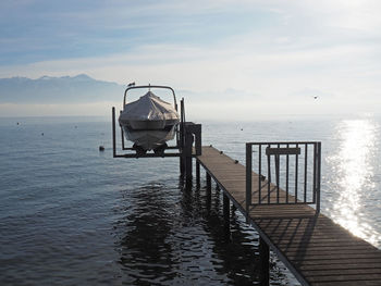 Close-up of covered boat moored at jetty in lake against sky