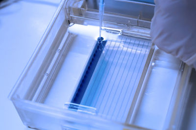 High angle view of chemical being poured from pipette on plastic in laboratory