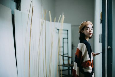 Close-up of young woman standing against wall