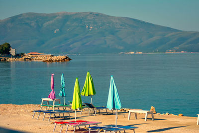 Chairs on beach by sea against mountains