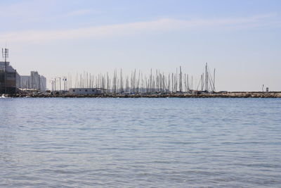 Sailboats in sea by buildings against sky