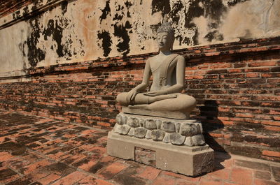 Statue against wall and old building