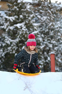 Winter portrait of a girl with a plastic sled sliding on a snowy slope 