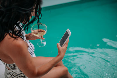 Midsection of man using mobile phone in swimming pool