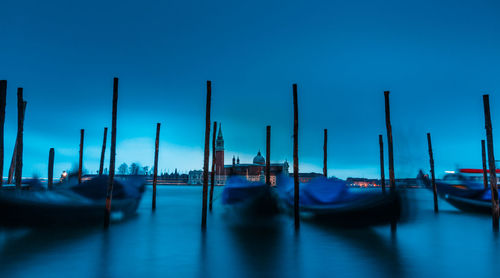 Boats moored in canal against blue sky