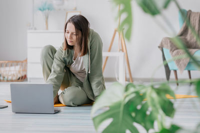 Woman using laptop sitting on floor