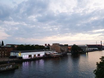 Buildings by river against sky in city