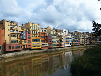 Buildings by river against sky