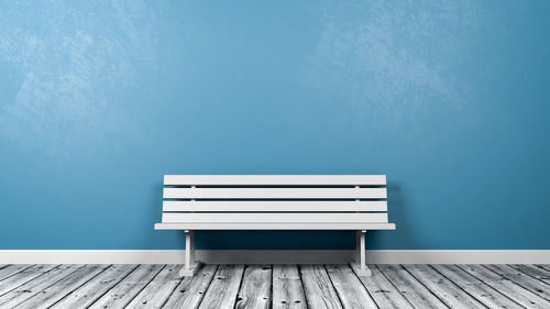 Empty bench against blue wall