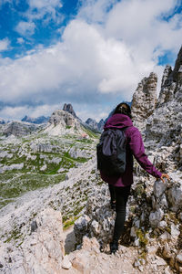 Rear view of man standing on rock against sky