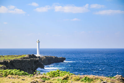 Lighthouse by sea against sky