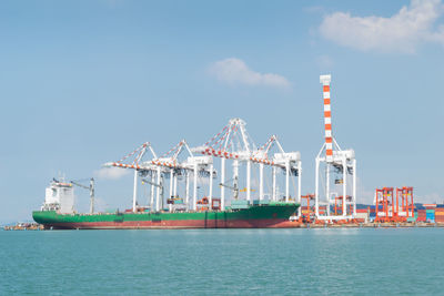 Container ship moored at commercial dock by sea against sky