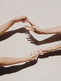 Cropped hands of women against gray wall