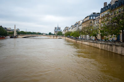 Flooded seine river by buildings in city against sky