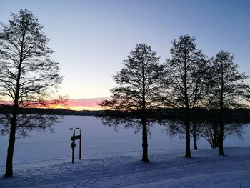 Silhouette trees by lake against sky during sunset