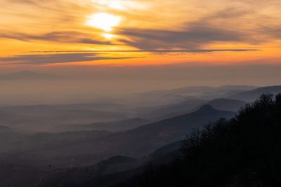 Scenic view of silhouette mountains against orange sky