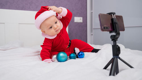 Portrait of cute baby girl sitting on bed at home