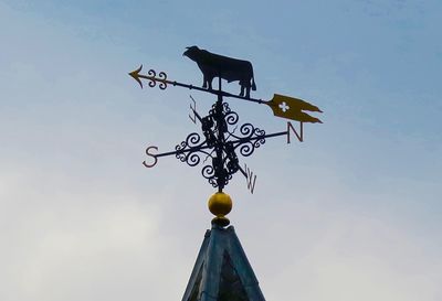 Low angle view of weather vane against sky