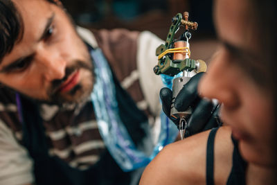 Artist making tattoo on woman shoulder at studio