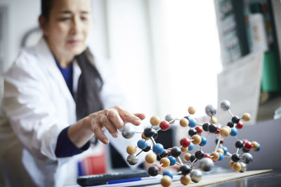 Mature teacher touching molecular structure on table at university chemistry laboratory