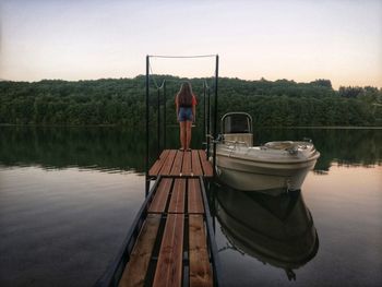Rear view of man standing on lake against sky
