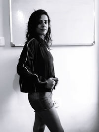 Portrait of young woman standing by whiteboard