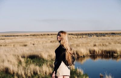 Rear view of woman standing on land against sky