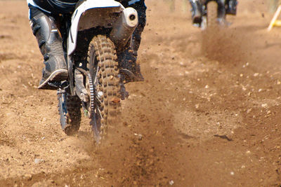 Low section of people riding motorcycle on dirt road