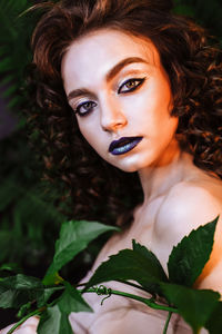 Portrait of beautiful redhead woman wearing make-up by plants