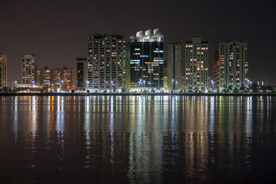 Illuminated buildings by river against sky at night in abu dhabi, united arab emirates