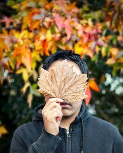 Portrait of man holding autumn leaves