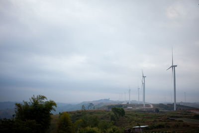 Wind turbines on landscape against sky