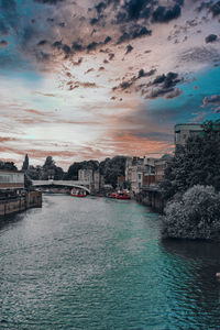 City at waterfront against cloudy sky