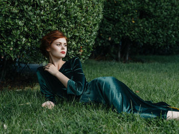 Young woman looking away while lying on lawn