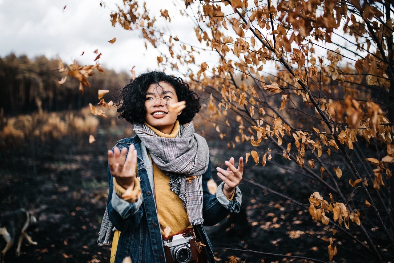 one person, real people, leisure activity, front view, lifestyles, smiling, happiness, standing, casual clothing, nature, young adult, focus on foreground, young women, autumn, land, portrait, plant, looking at camera, holding, outdoors, leaves, change, hairstyle