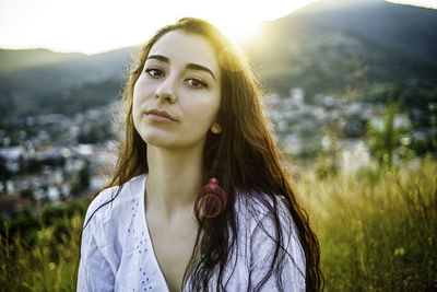 Portrait of beautiful young woman standing against plants