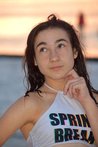 Teenage girl standing by sea against sky during sunset