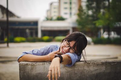 Cheerful teenage girl sitting on bench in city