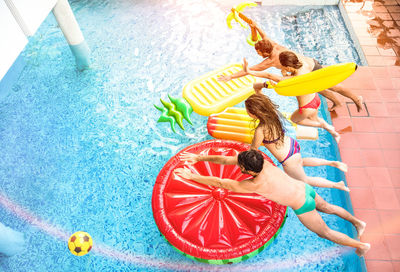 High angle view of friends jumping in swimming pool