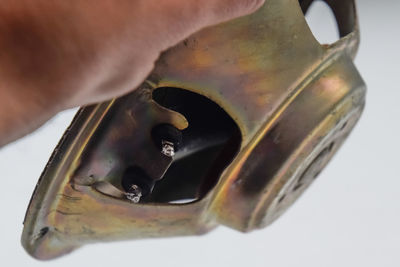 Close-up of hand holding metal against white background