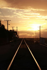 Railroad tracks against sky during sunset