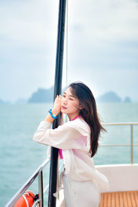 Rear view of young woman standing against sea