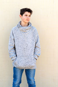 Portrait of a teenage boy looking away against yellow wall