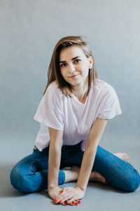 Portrait of a smiling young woman sitting against wall