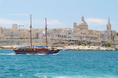 Boats in sea by city against sky