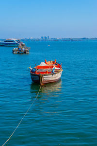 Fishing boats moored in sea against clear sky