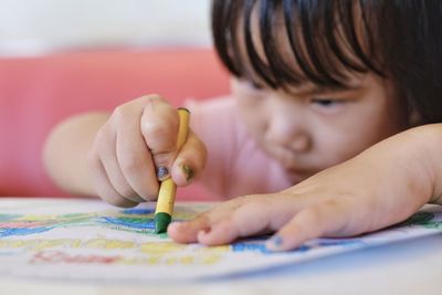 Close-up portrait of baby girl painting on the paper 