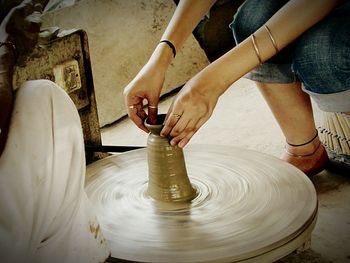 Midsection of female potter making pots at workshop