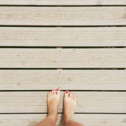 Low section of woman walking on wooden floor